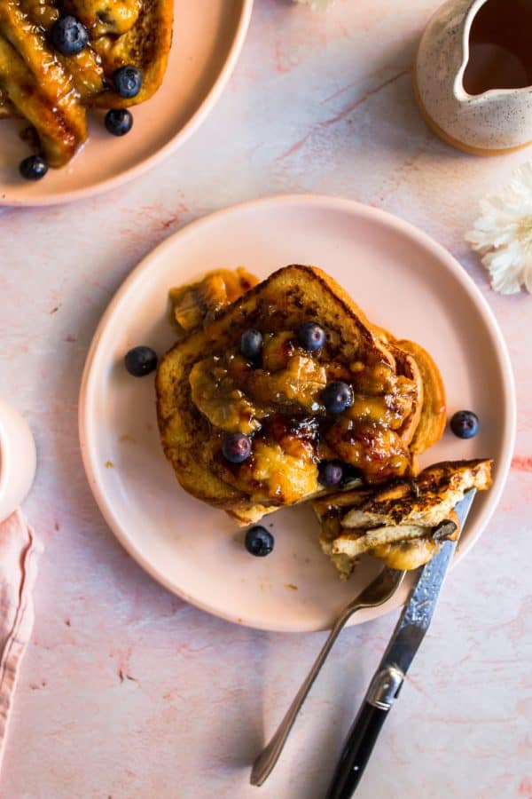 Cooked french toast on a pink plate with a fork and knife