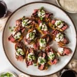 Steak crostini on a plate with balsamic glaze.