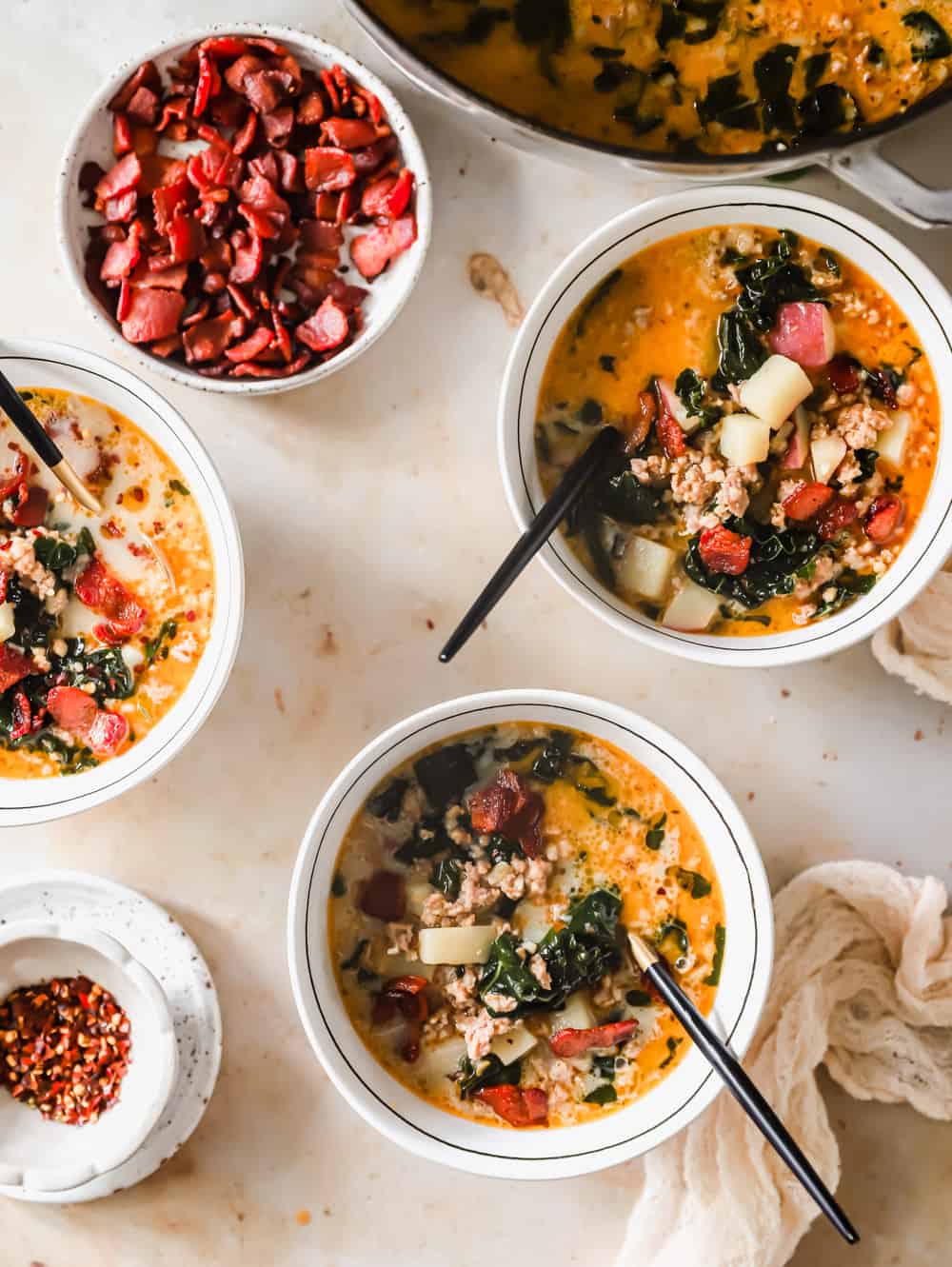 3 white bowls filled with zuppa toscana soup.
