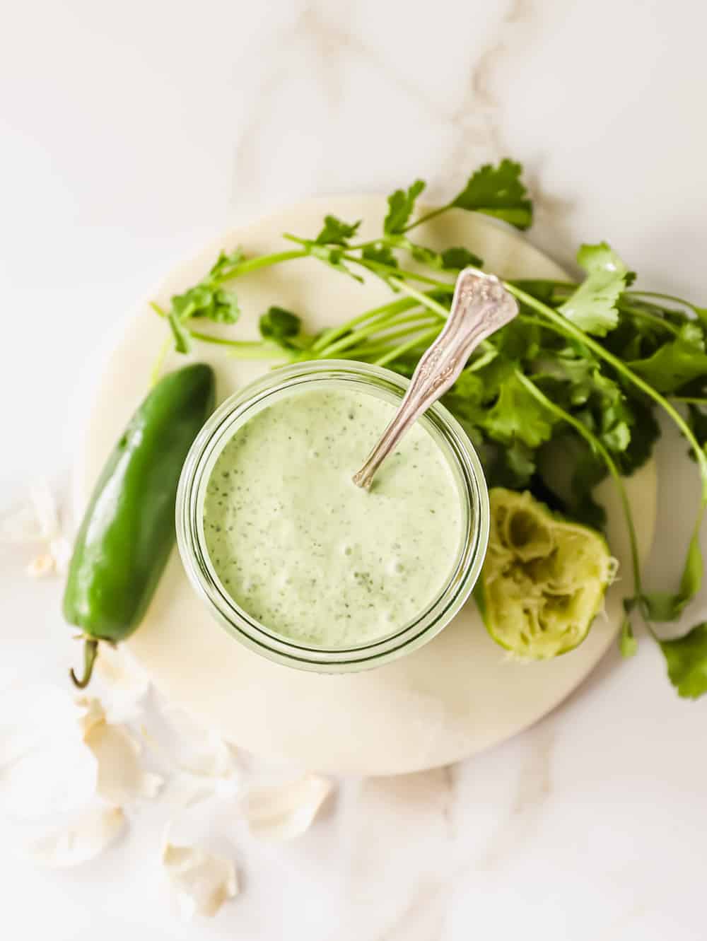 overhead view of a small mason jar filled with creamy green Peruvian sauce.