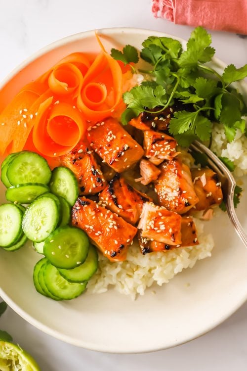 Fresh vegetables, rice, and cooked salmon bites.
