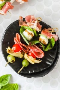 Two antipasto skewers on a plate.
