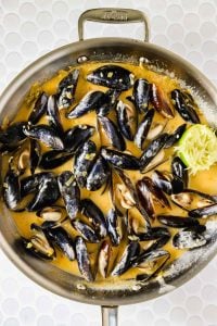 Coconut curry mussels in a pan.