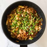 Skillet with noodles, ground beef, and scallions.