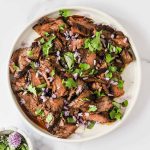 Slices of marinated steak with garnishes.