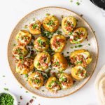 Baby potatoes with toppings on a platter.