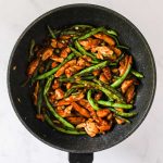 Cooking chicken and green beans together.