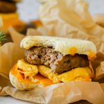 A bitten breakfast sandwich wrapped in parchment.