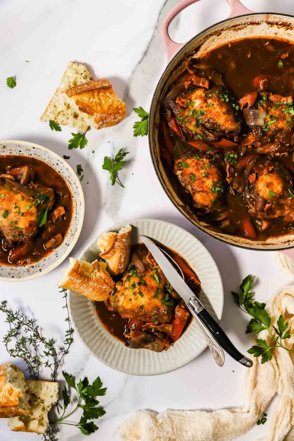 Chicken coq au vin in a bowl and a pot.