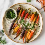 Overhead shot of air fryer carrots on a plate topped with parmesan cheese and freshly chopped parsley.