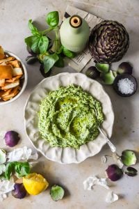 Overhead shot of easy artichoke dip with a slightly chunky yet creamy texture with visible arugula specks.
