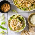 Overhead shot of chicken caesar pasta salad with shaved parmesan cheese on top.