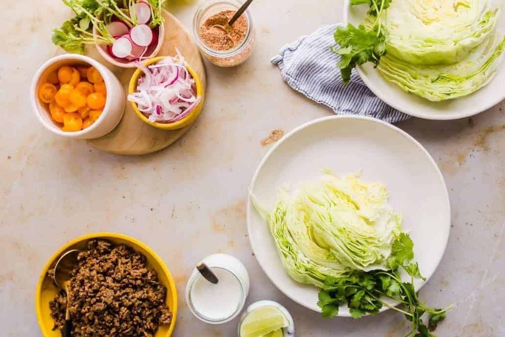 Toppings for the Healthy Taco Bowls With Mexican Beef. Tomatoes, lettuce, lime, cilantro, taco seasoning, and onion.