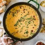 Overhead shot of a pot with cajun potato soup, garnished with chopped green onions.