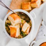 White bowls filled with chicken pot pie topped with puff pastry squares; a spoon rests in one bowl. Text overlay reads, "Easy Chicken Pot Pie" and "LenasKitchenBlog.com.