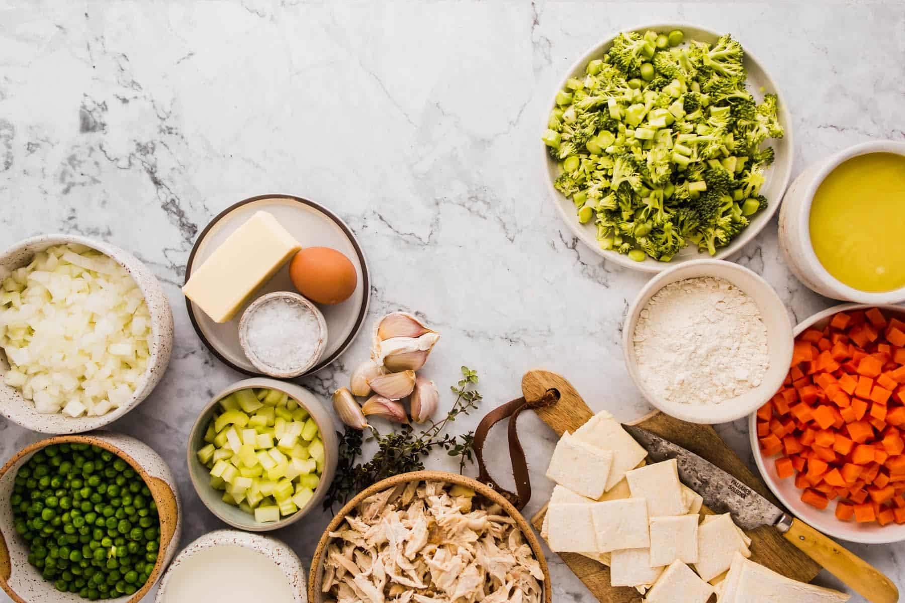 Ingredients for Quick and Easy Homemade Chicken Pot Pies with Puff Pastry. Using peas, onion, celery, salt, butter, egg wash, garlic, thyme, chicken, milk, brocolli, puff pastry, chicken stock, carrots, and flour. 
