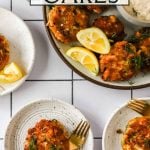 Overhead view of crab cakes served on plates with lemon wedges and dipping sauce on a white tiled surface.