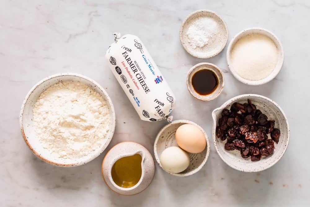 individual white bowls holding dried cherries, flour, eggs, sugar, and oil