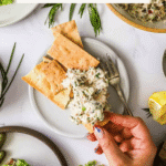 A hand holds a cracker topped with tuna salad above a plate; near it are more crackers, greens, lemon, and a bowl of tuna salad. Text reads “Healthy Tuna Salad” and “LenasKitchenBlog.com”.