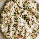 A bowl filled with lemon herb tuna salad mixed with fresh herbs and vegetables, shown from above. Text on the image promotes a healthy, easy tuna salad recipe from LenasKitchenBlog.com.