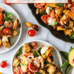 Plates of panzanella salad with tomatoes, bread, onions, and basil on a white table, surrounded by whole tomatoes and peach slices. Text reads “Easy Summer Salad Panzanella Salad.”.