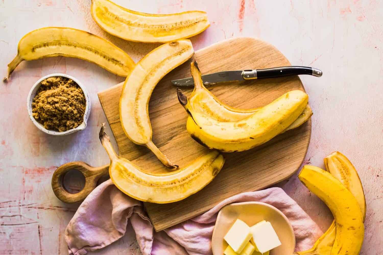 Slicing bananas on a cutting board with brown sugar and butter on the side