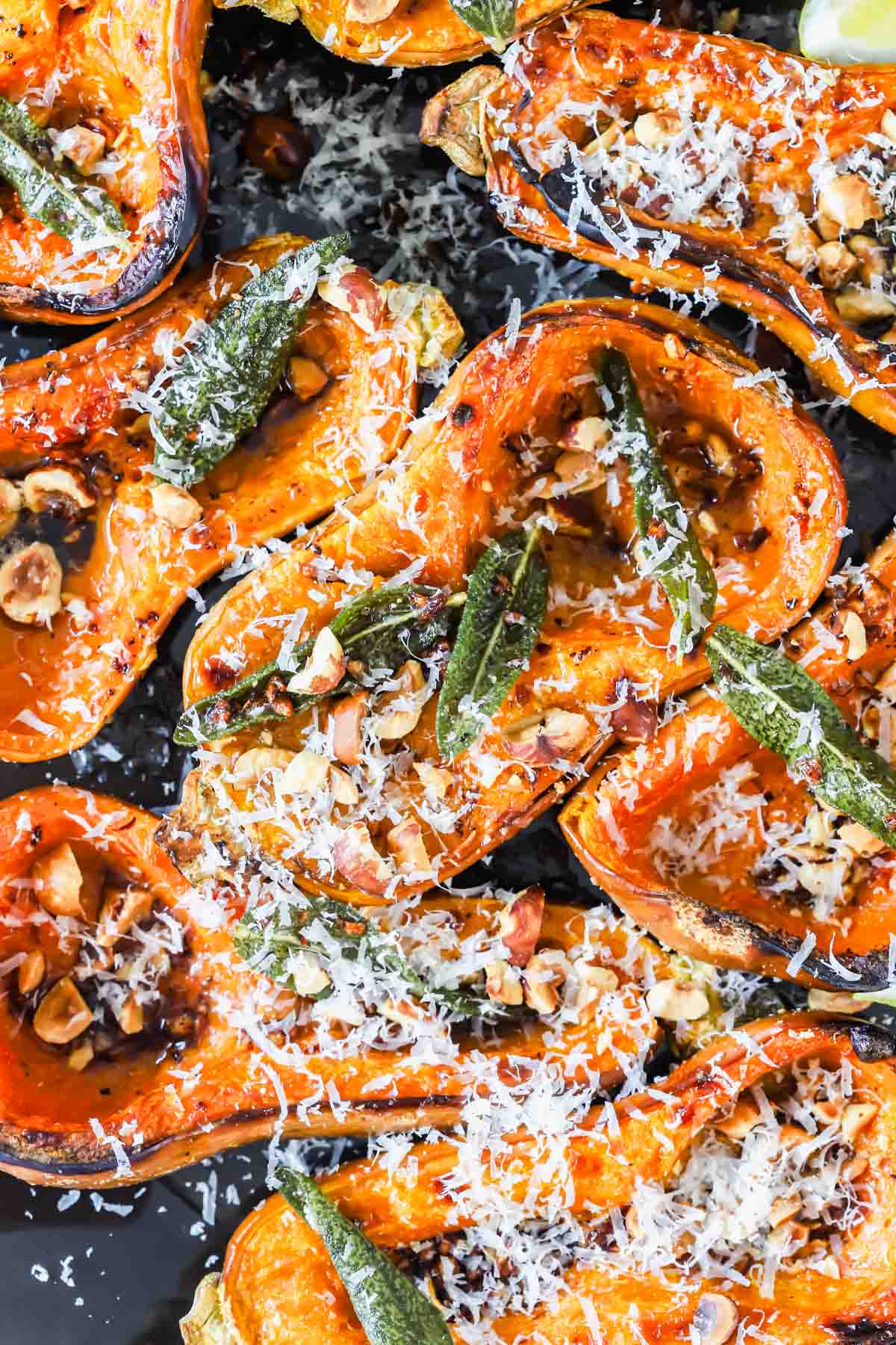 Roasted butternut squash halves topped with fried sage, chopped nuts, and grated cheese.